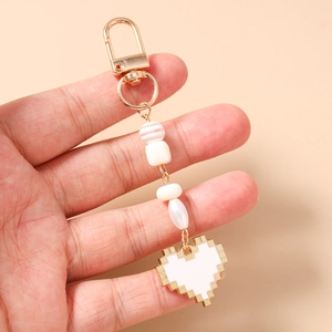 Detail of pixel heart keychain with gold clasp and assorted beads held in hand