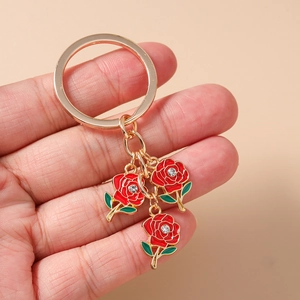 Detail view of gold alloy keychain with three red enamel roses and crystal center