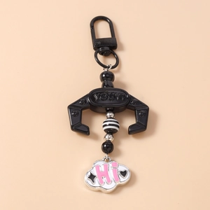 Detail of mechanical claw keychain featuring black beads and a cloud charm with HI text