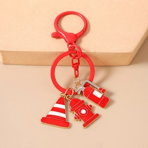 Detail of red fire hydrant keychain with extinguisher and traffic cone enamel charms