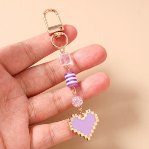 Macro shot of purple pixelated heart keychain with colorful beads and golden clasp