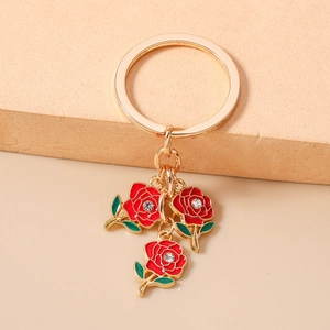 Detailed macro of golden keychain with three red enamel roses and crystal accents