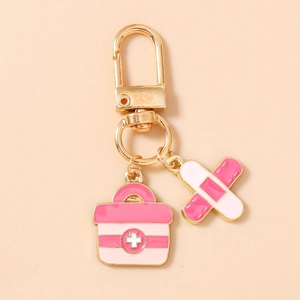 Detail showing pink first aid kit and bandage enamel charms on a gold keychain