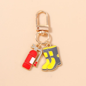 Detailed view of red fire extinguisher and yellow boots enamel charms on golden keychain