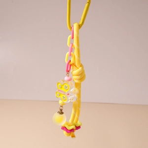 Détail d'une chaîne de téléphone jaune tressée avec pendentif papillon et mousqueton métal