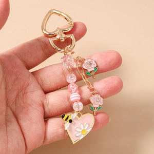 Dettaglio del portachiavi a cuore rosa con perline e ciondoli a rosa tenuto in mano