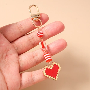 Detail of red pixel heart keychain with gold metal clasp and decorative striped beads