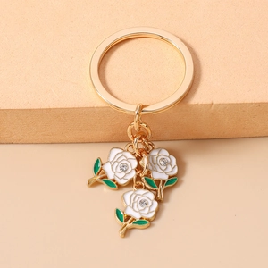 Detail of elegant gold rose keychain with white enamel petals and sparkling rhinestones