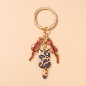 Détail de trois charms chat sur un porte-clés doré avec des queues mobiles et amusantes