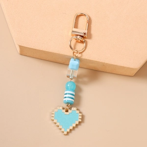 Detailed view of turquoise pixel heart keychain with gold clasp and assorted beaded charms