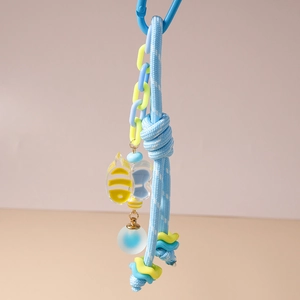 Détail d'un porte-clés tressé bleu avec un pendentif abeille et un maillon en acrylique
