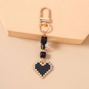 Close-up of golden pixel heart keychain with elegant black and transparent beads