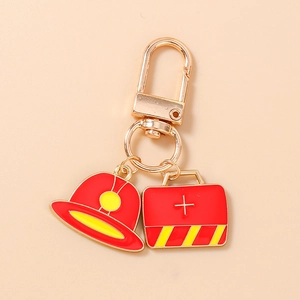 Detailed view of firefighter helmet and medical kit charms on gold metal keychain