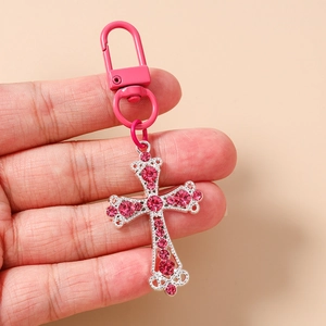 Détail d'un porte-clés croix orné de cristaux roses avec un fermoir mousqueton rose