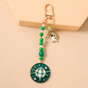 Détails du porte-clés astronaute avec perles vertes et pendentif lune dorée sur fond rose