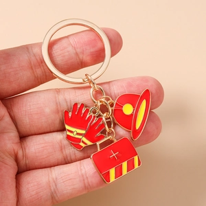 Close-up of enamel firefighter keychain with helmet, glove and first aid kit charms