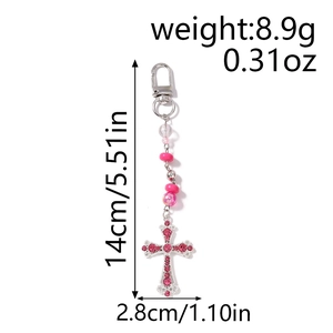Détail du porte-clés perlé montrant une longueur de 14 cm et un pendentif croix rose