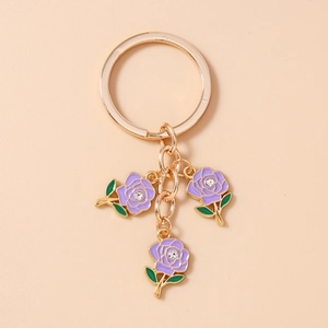 Macro view of gold metal keychain featuring purple enamel roses and crystal accents