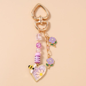 Dettaglio portachiavi a cuore con fiori viola, motivi ape e chiusura dorata