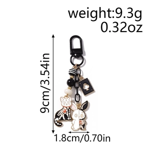 Detail showing cartoon skeleton cat, rabbit, and ace of spades poker pendants on a keychain