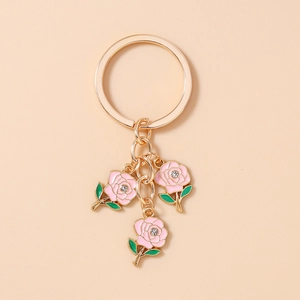 Detail of three pink enamel roses keychain with golden ring and small crystal accents