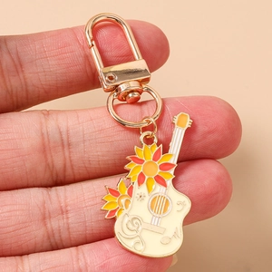 Détail macro du porte-clés guitare en émail avec tournesol et fermoir mousqueton doré
