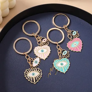 Détail de quatre porte-clés cœur mauvais œil colorés avec main de Hamsa sur plateau