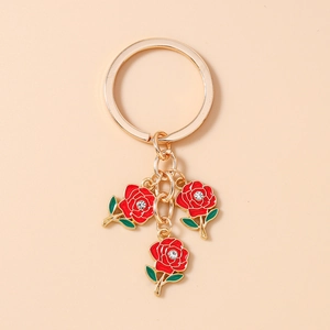 Close-up of golden keychain featuring three red enamel roses with sparkling white crystals