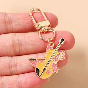 Détail d'un porte-clés violon émaillé jaune avec fleurs roses et fermoir doré chic