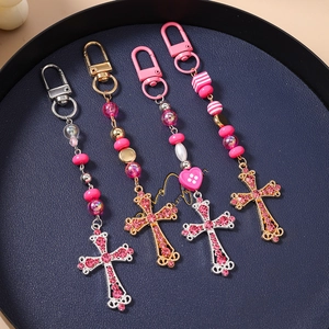 Gros plan de porte-clés croix en strass rose avec perles rayées sur un plateau
