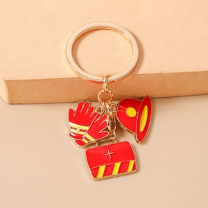 Detail of firefighter keychain featuring red enamel charms of helmet, glove and emergency bag