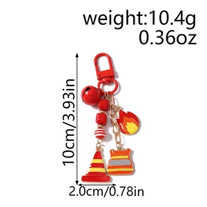 Detailed macro shot of firefighter keychain with red hook, bell and safety vest charms