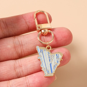 Détail d'un porte-clés harpe doré avec motifs floraux en émail bleu et blanc