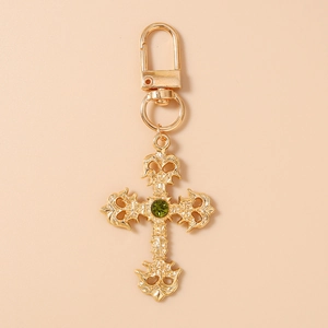 Détail du porte-clés croix gothique dorée avec motifs ajourés et pierre verte