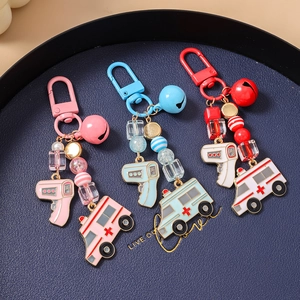 Detail of medical theme keychains with ambulance charm and thermometer pendants on blue tray