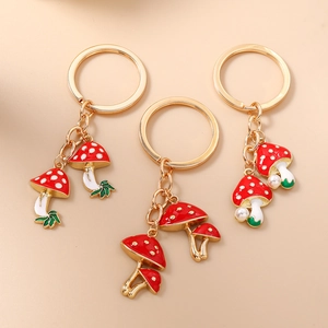 Three red mushroom keychains with white dots, green leaves, and gold metal keyrings