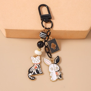 Detailed close-up of dark gothic cat and rabbit skeleton enamel charms with poker card