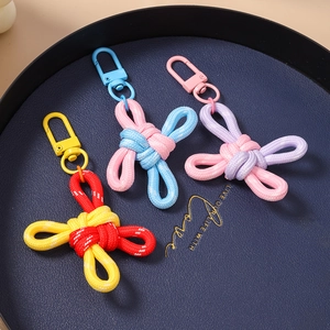 Three colorful handmade woven Chinese knot keychains with painted D-buckles on a blue tray
