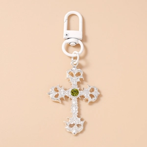 Détail du porte-clés croix gothique argentée avec gemme vert olive et fermoir blanc laqué