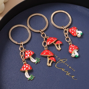 Three stylish mushroom keychains with red enamel heads and gold-toned finish for bag charms