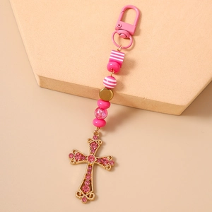 Détail des perles rayées roses et du pendentif croix avec des cristaux roses