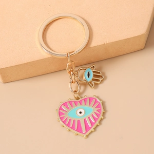 Vue détaillée du pendentif cœur rose avec œil et main de Fatma dorée sur un porte-clés