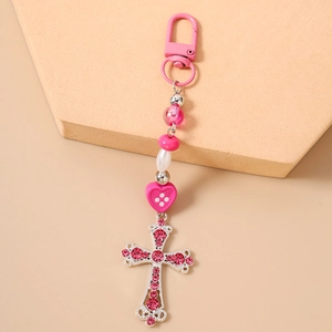Détail du porte-clés à perles roses avec croix en strass sur support beige