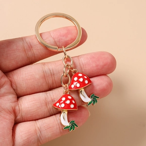 Detail of red enamel mushroom charms and golden alloy key ring held in hand