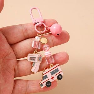 Pink medical-themed keychain featuring detailed enamel charms of an ambulance and thermometer