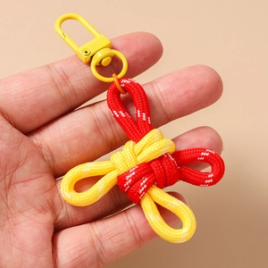 Close-up of a hand holding a red and yellow braided cord keychain with a metal hook