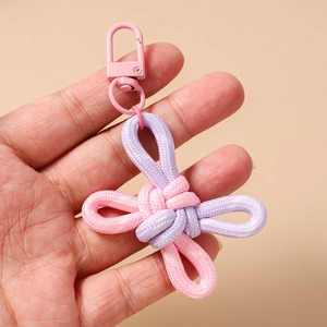 Detailed view of handmade pink and purple woven knot keychain held by hand