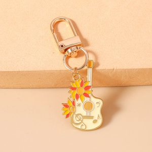 Détail d'un porte-clés guitare avec motif tournesol et fermoir mousqueton doré