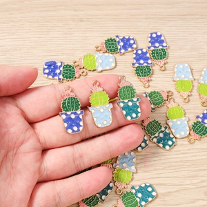 Détail macro de breloques cactus en émail pour bijoux avec des petites fleurs roses