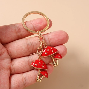 Detail of red mushroom keychain with gold plating and white dots held in hand